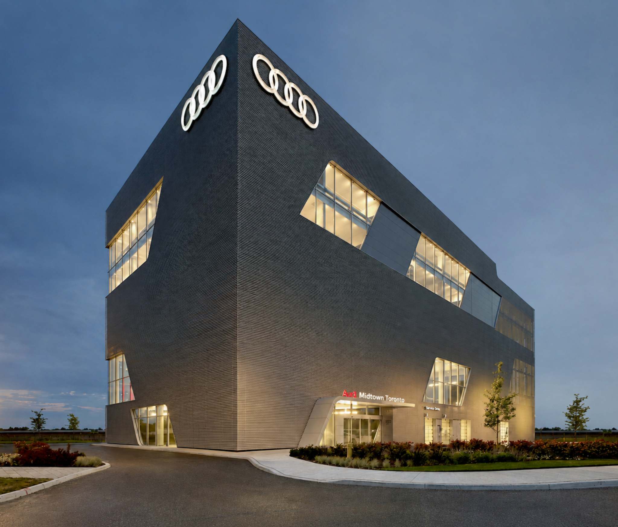 Audi Midtown Toronto at dusk, its illuminated windows set into the angular building.